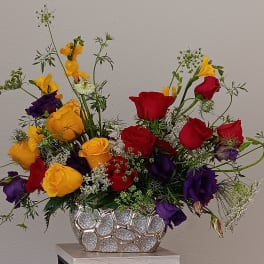 Bouquet of red, yellow, and purple roses in a silver vase