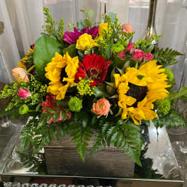 Mixed bouquet with sunflowers, red gerbera daisies, and pink roses in a wooden box
