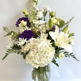 White and purple floral arrangement in a clear glass vase