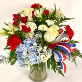 Bouquet of red and white flowers with blue hydrangeas in a glass vase