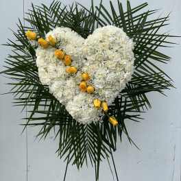 Heart-shaped white floral spray with yellow roses on a stand