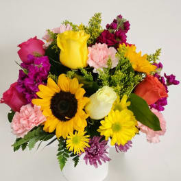 Mixed bouquet with sunflowers, roses, and carnations in a white vase