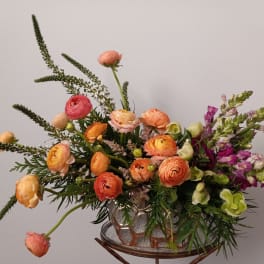 Mixed bouquet of orange and pink flowers in a glass vase