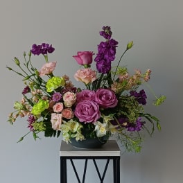 Mixed bouquet of pink and purple flowers in a low black bowl