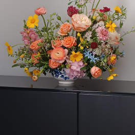 Mixed bouquet in a blue-and-white vase with pink, peach, and yellow flowers