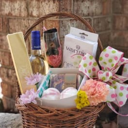 Gift basket with wine, chocolates, bath items, and flowers
