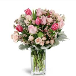 Pink tulips and roses arranged in a clear glass vase