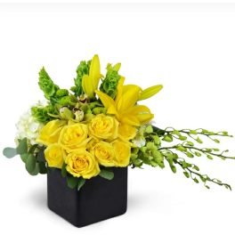Yellow roses and lilies in a black square vase