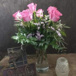Pink roses in a glass vase with greenery and small filler flowers