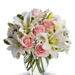 Pink roses and white lilies arranged in a clear glass vase