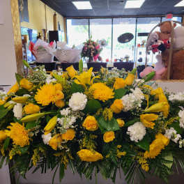 Large yellow and white floral arrangement with roses, lilies, and chrysanthemums