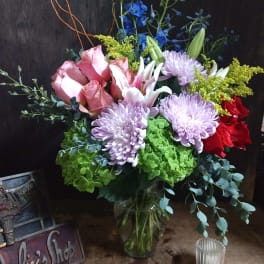 Mixed bouquet in a glass vase with pink roses, lavender mums, and lilies