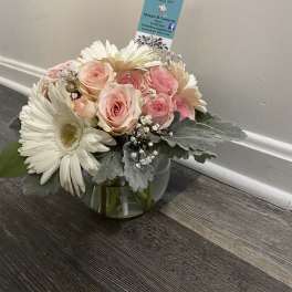 Pink roses and white daisies arranged in a glass bowl vase