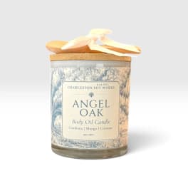 A labeled candle jar with a wooden lid and ribbon bow