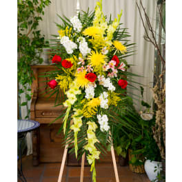 Tall standing spray of yellow, white, and red flowers arranged on a wooden easel