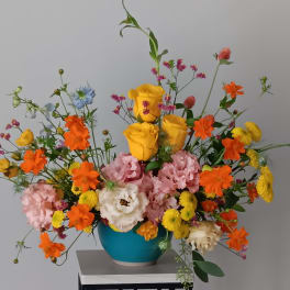 Colorful mixed bouquet in a blue vase with yellow roses and orange blooms
