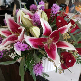 Bouquet of pink-and-white lilies and red roses in a white vase