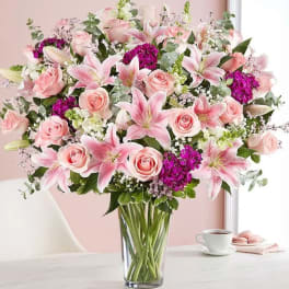 Pink lilies and roses arranged in a clear glass vase