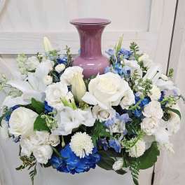 White and blue floral arrangement around a purple vase
