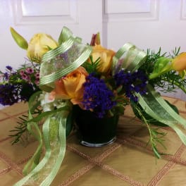 Bouquet of yellow roses and orange tulips in a glass vase with ribbon