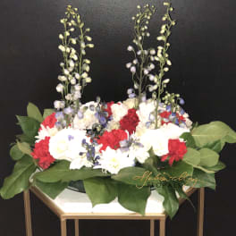 Red and white floral arrangement with tall lavender stems in a gold stand