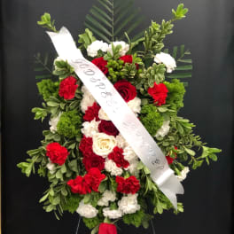 Standing floral spray with red and white flowers and a white ribbon