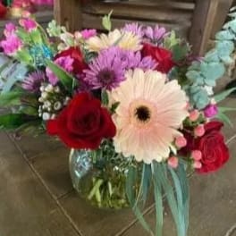 Mixed bouquet with red roses and pink gerbera daisies in a glass vase