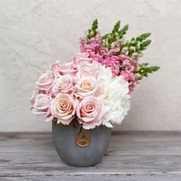 Pink and white roses arranged in a gray vase