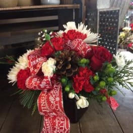 Red and white floral arrangement in a dark vase with a holiday ribbon