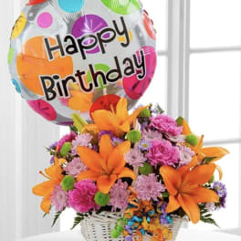 Birthday balloon above a colorful flower basket in a white basket
