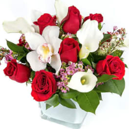 Red roses and white calla lilies in a clear glass vase