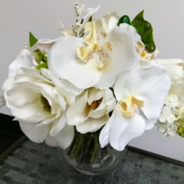 White orchids and tulips arranged in a clear glass vase