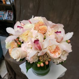 Blush and cream bouquet with roses and orchids in a glass vase