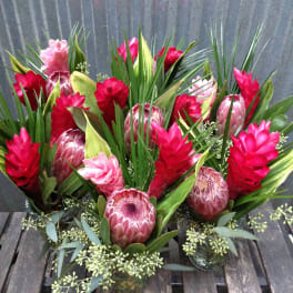 Tropical floral arrangements with red and pink blooms in small glass vases