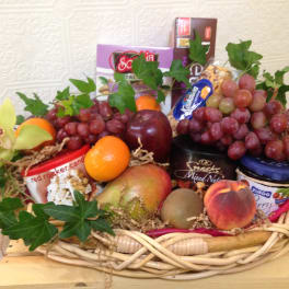 Fruit basket with grapes, oranges, mango, kiwi, peach, and packaged snacks