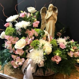 Basket of pink and white flowers with an angel figurine
