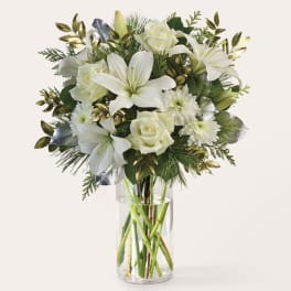 White lilies and roses arranged in a clear glass vase