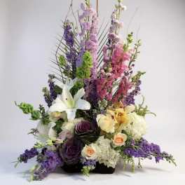 Tall mixed floral arrangement with lilies, roses, and purple blooms