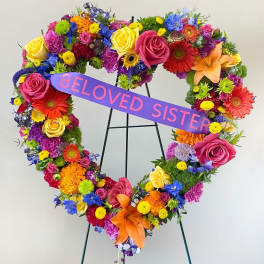 Heart-shaped floral wreath with a purple ribbon reading "BELOVED SISTER"