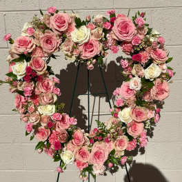 Heart-shaped floral wreath of pink and white roses on a stand