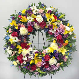 Large circular floral wreath with mixed colorful flowers on a stand