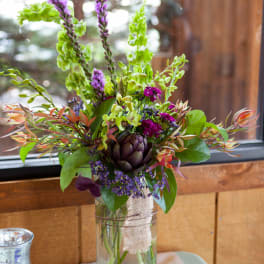 Mixed floral arrangement in a clear glass vase with purple and green blooms