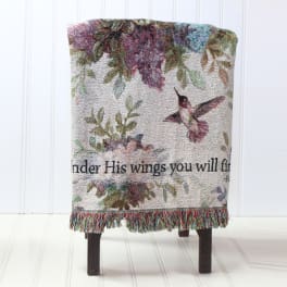 Decorative woven throw with hummingbirds and floral pattern draped over a chair