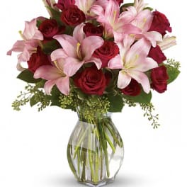 Bouquet of pink lilies and red roses in a clear glass vase