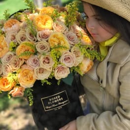 Large bouquet of peach and cream roses in a black box