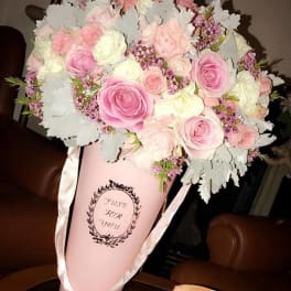 Pink and white rose bouquet in a pink cone wrap with ribbon