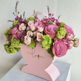 Pink rose bouquet in a heart-shaped box with green accents