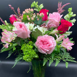 Pink roses and alstroemeria in a green glass vase