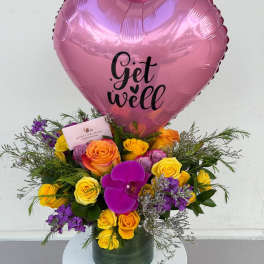 Pink heart balloon above a colorful rose bouquet in a vase