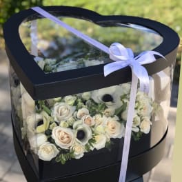 Heart-shaped black box with white roses and a ribbon bow